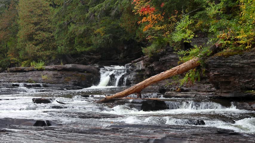 Beautiful mountain river flowing over rocky steps in Black river national forest in Michigan upper peninsula during the fall season.