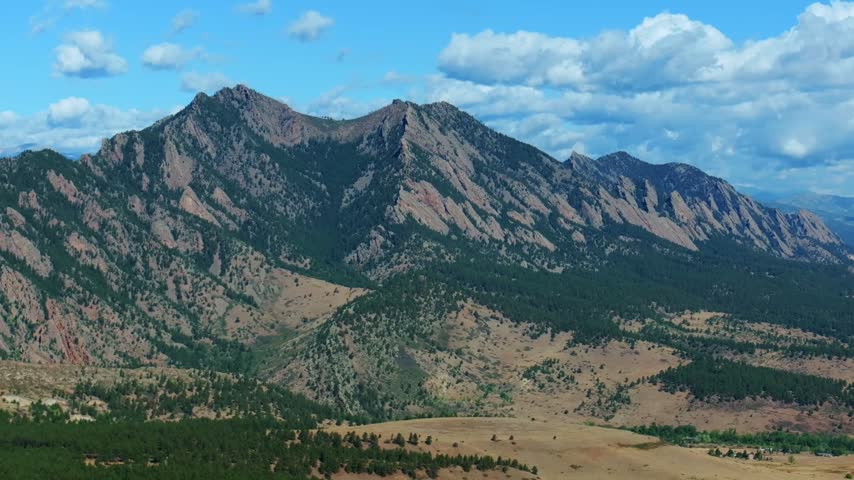 Aerial drone view South Boulder vista of the The Flatirons Colorado summer fall autumn morning sunny blue sky Front Range Rocky Mountains Foothills City of Boulder nature landscape circle left motion