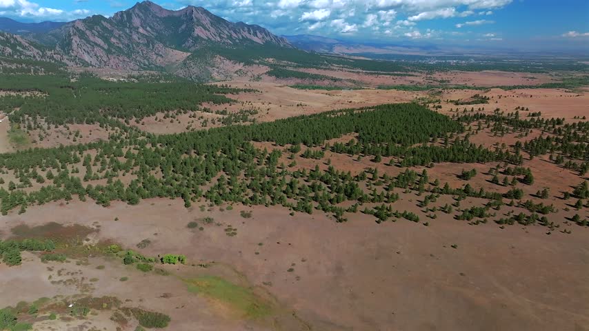 Aerial drone view vista of South Boulder of the The Flatirons Colorado summer fall autumn morning sunny blue sky Front Range Rocky Mountains Foothills City of Boulder nature landscape forward pan up