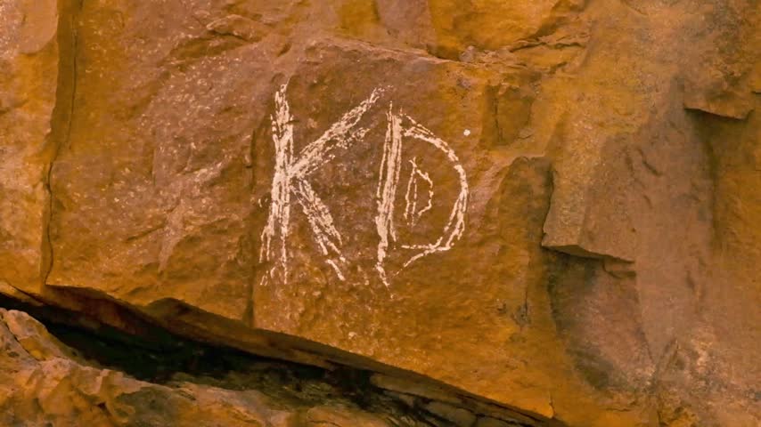 Graffiti of the letters K and D scratched onto a cliff face