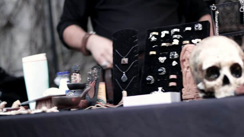 Hands supporting and arranging an antique skull in a medieval shop, for sale and fortune-telling.