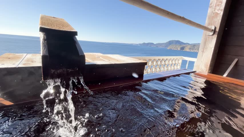 Hot spring rotenburo with ocean view and wooden hot water spout in Izu Inatori, Shizuoka, Japan.