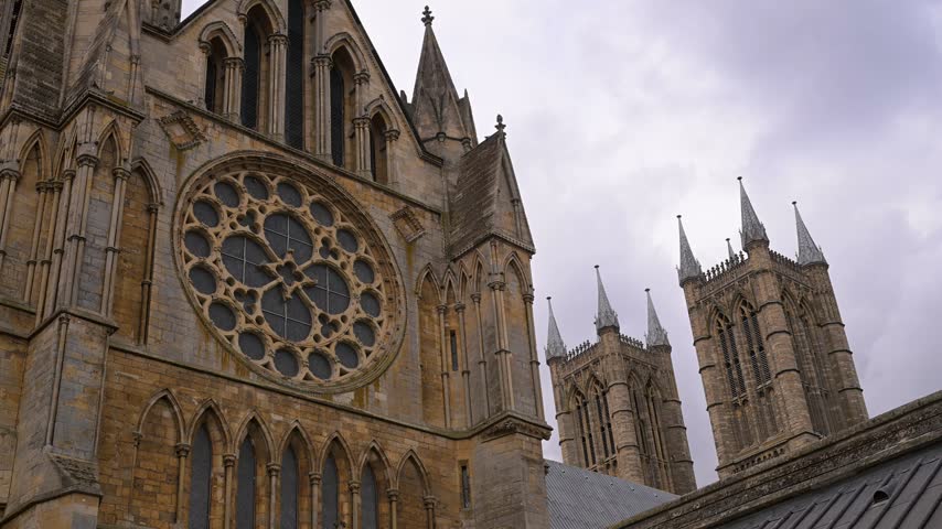 Lincoln Cathedral’s ornate rose window and twin towers fill the frame as the camera slowly pushes in under overcast skies.