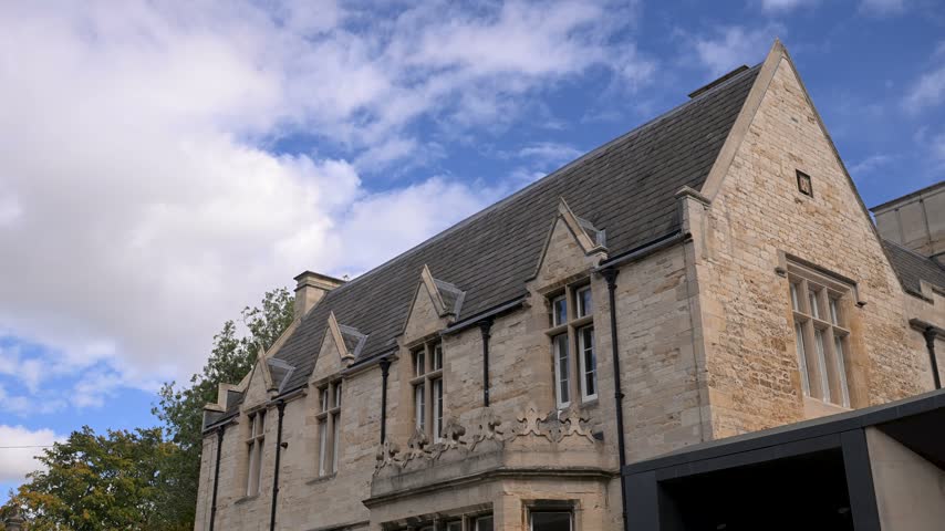 Old stone gift shop building with steep slate roof sits under a bright blue sky as the camera holds steady on the facade.