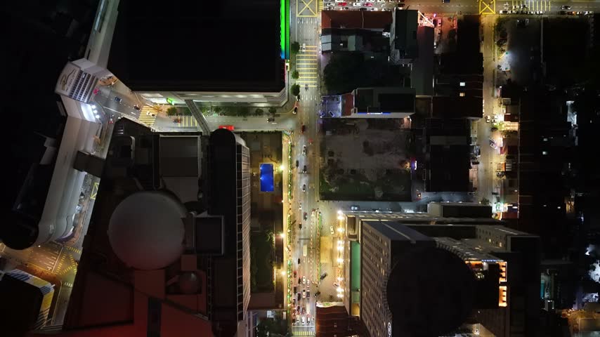 Nighttime aerial cityscape of George Town, Penang, with illuminated roads, buildings, parked cars, and active urban traffic.