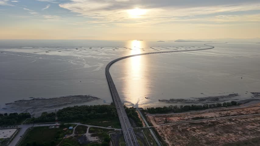 Penang Second Bridge crosses coastal waters and tidal flats beneath warm evening sunlight in Malaysia.