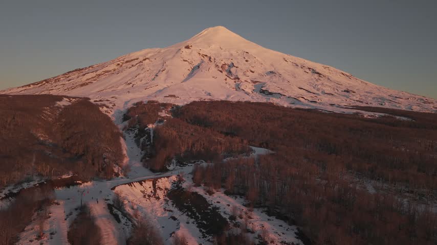 Alpenglow on Villarrica volcano with snowy lava channels, aerial