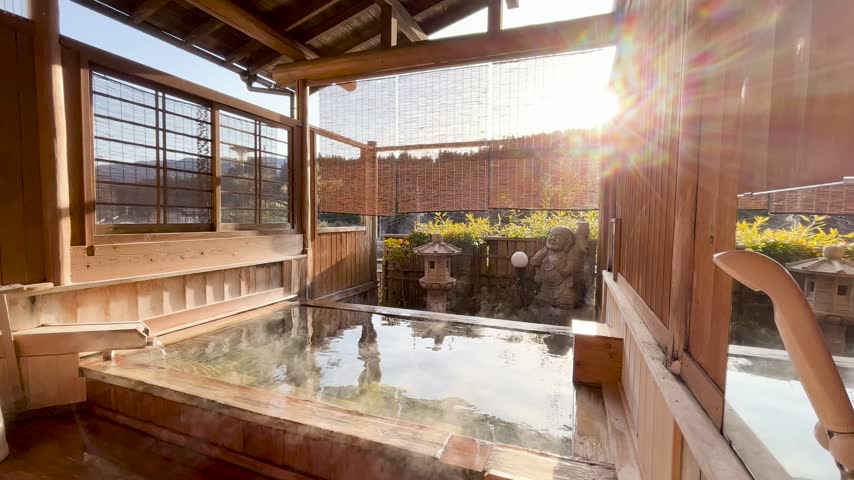 Scenic view of a traditional Japanese wooden open-air hot spring rotenburo with warm sunlight in Japan.