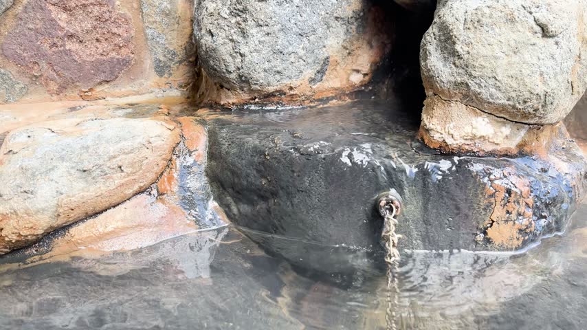 Close-up of hot spring water springing from rock formations in Japan.