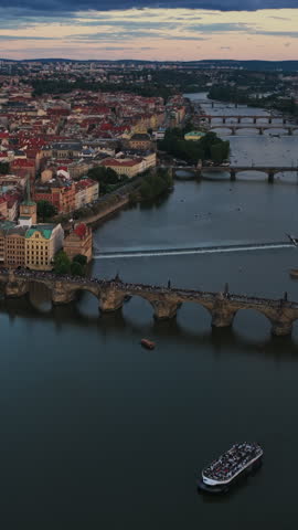 Iconic Charles Bridge Spanning Vltava River With Multiple City Bridges And Urban Skyline At Sunset In Prague, Czech Republic. - aerial vertical shot