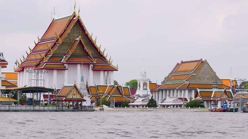 Tracking shot of Wat Kalayanamit Buddhist temple complex along the Chao Phraya River in Bangkok.