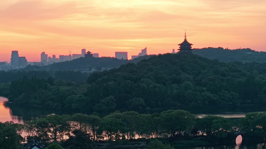 Sunrise over Leifeng Pagoda and West Lake in Hangzhou, China, with golden morning light reflecting on the water.