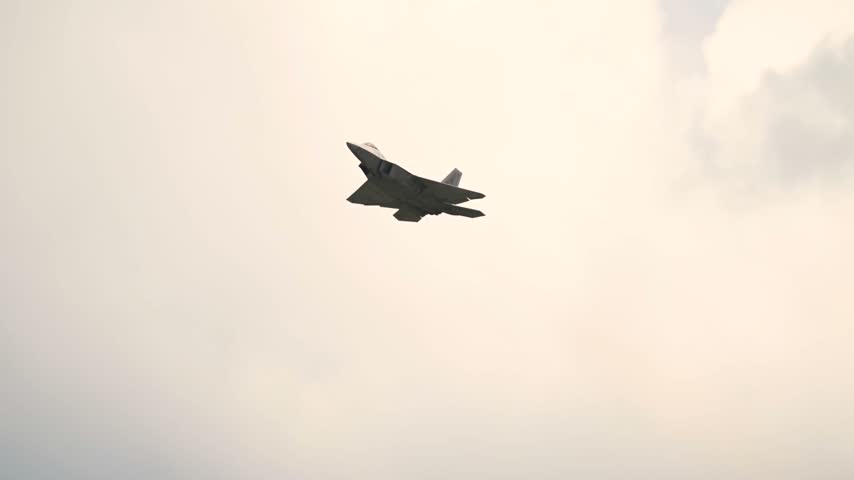 An F-22 Raptor Stealth Fighter Soars Gracefully Through The Sky During High-Speed Aerial Maneuvers.