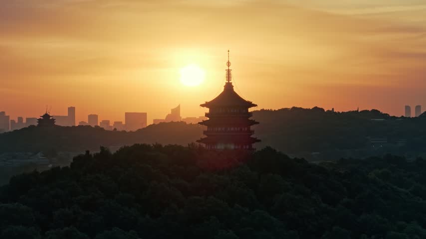 Sunrise over Leifeng Pagoda and West Lake in Hangzhou, China, with golden morning light reflecting on the water.