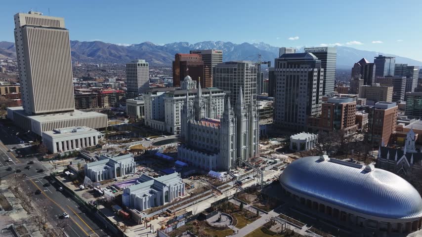 Dolly-out aerial drone wide shot of the famous Salt Lake City Temple under construction, a Latter-day Saints landmark in downtown Salt Lake City, Utah, on a sunny, February day