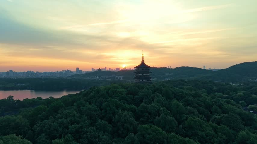 Sunrise over Leifeng Pagoda and West Lake in Hangzhou, China, with golden morning light reflecting on the water.