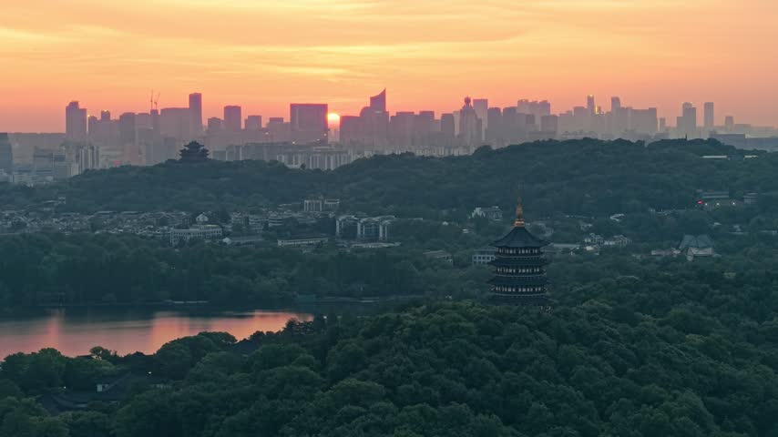 Sunrise over Leifeng Pagoda and West Lake in Hangzhou, China, with golden morning light reflecting on the water.
