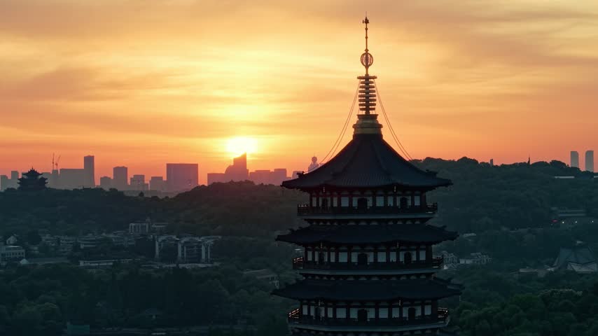 Sunrise over Leifeng Pagoda and West Lake in Hangzhou, China, with golden morning light reflecting on the water.