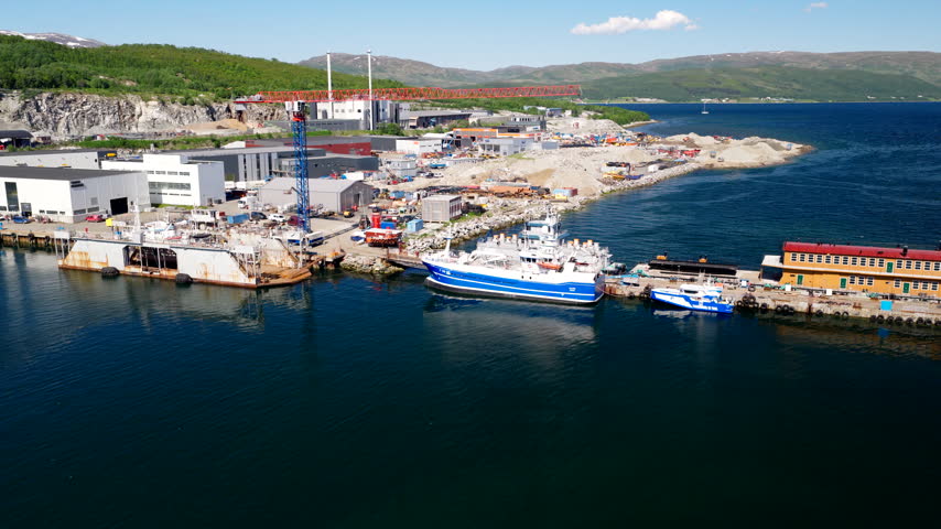 Fishing boat docked next to a dry dock for maintenance at an industrial shipyard in Tromso, Norway. Aerial approach