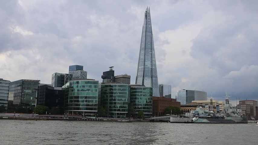 Camera pans across the River Thames in the opposite direction, moving from the Shard skyline toward Tower Bridge and the London waterfront.