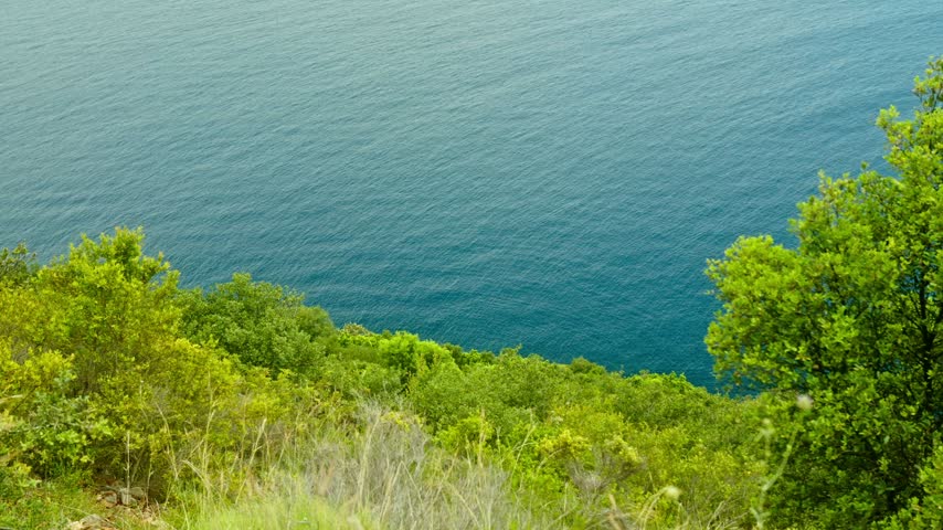 Albania, Vlore 2023 05 27: Canyon of Gjipe landscape showcasing green forested cliffs overlooking the deep blue sea, captured in a wide angle horizontal shot perspective.