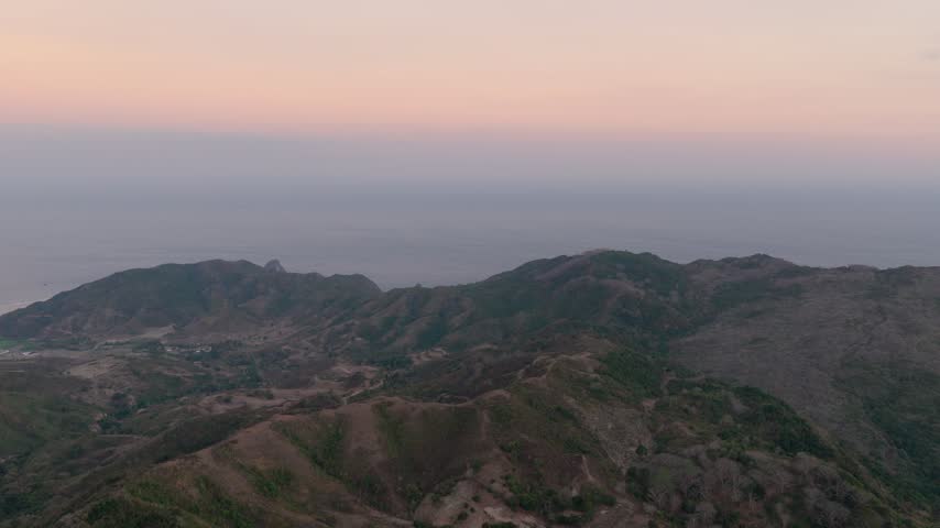 Kuta in southern Lombok, Indonesia, features a rugged mountain ridge silhouetted against warm sunset colours, highlighting rocky peaks and the dramatic tropical landscape of West Nusa Tenggara