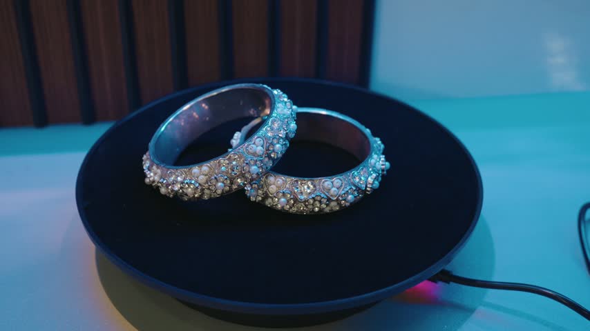 Top angle close up of pair of decorative bangles placed on a motorized rotating display turntable