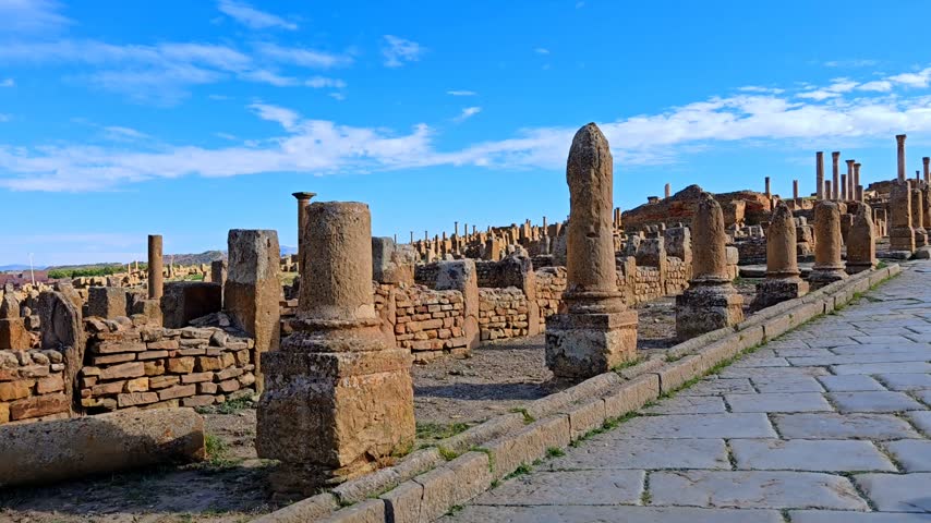 Ancient Roman ruins of Timgad with the Arch of Trajan under a clear blue sky in Algeria