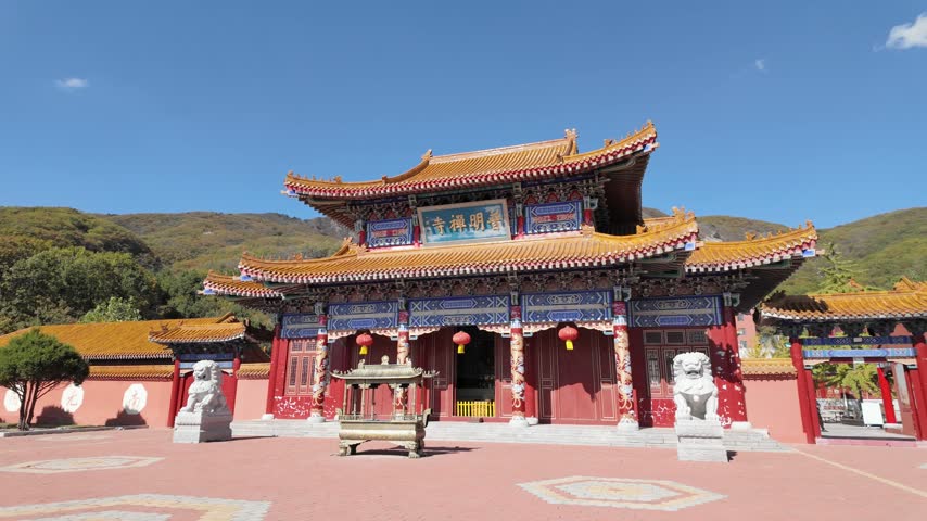 Circular view of the ornate main entrance gate of a traditional Chinese Buddhist temple with stone guardian lions at the foot of a mountain, ancient temple site in Dalian, China