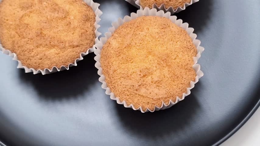 Fresh-baked cupcakes in paper liners on a black plate