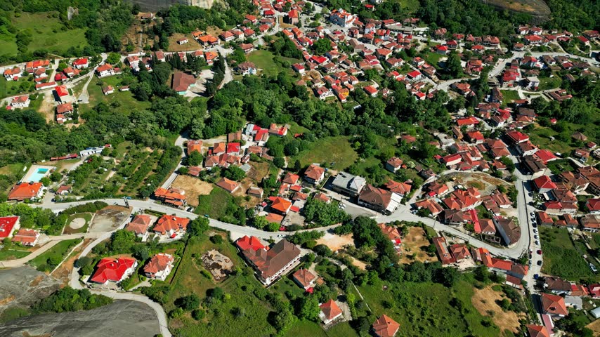 Aerial view of the town of Trikala with red-roofed houses and lush green surroundings in Trikala, Greece.