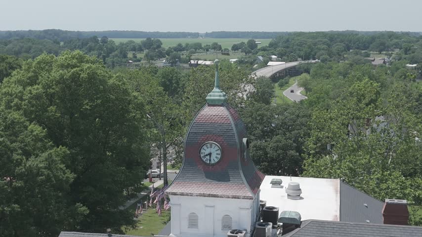 Aerial drone orbit around the historic Caroline County Courthouse cupola and clock with the town and Choptank River beyond, Denton, Maryland, USA.