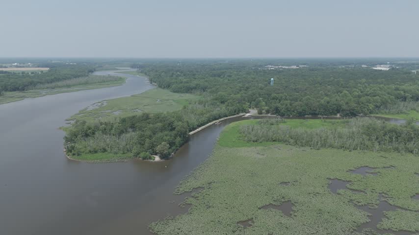 Aerial drone view over a wooded island and green marsh in the wide Choptank River on a hazy summer day, Denton, Maryland, USA.