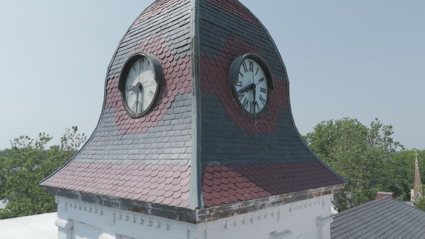 Aerial drone flight past the clock faces and shingled dome of the historic Caroline County Courthouse cupola toward the town, Denton, Maryland, USA.