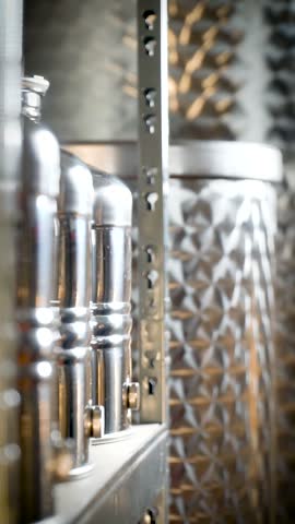 Stainless steel barrels are lined up on a metal shelf in a spirits distillery