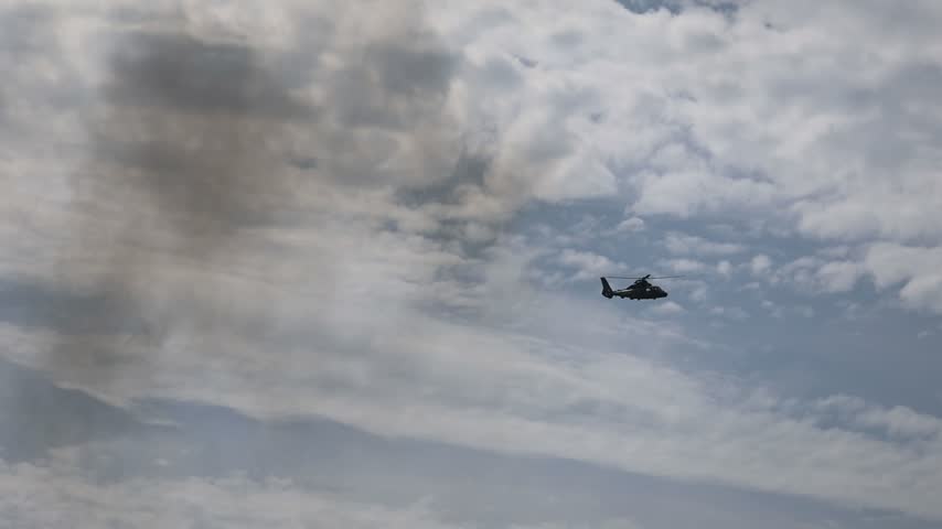 A helicopter appears near the edge of a ferry structure against a textured cloudy sky during a Channel crossing near Calais.