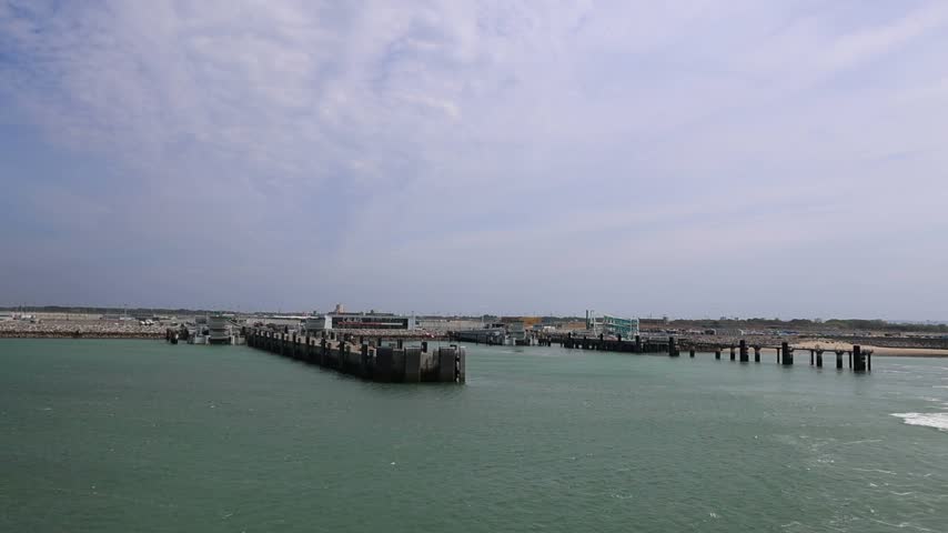 A wide view of the ferry harbor at Calais, France, with breakwaters and vessels along the coast of the English Channel.
