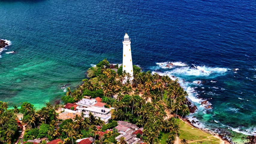 Aerial view of Dondra Lighthouse surrounded by lush palm trees and turquoise ocean waters in Dondra, Southern Province, Sri Lanka.