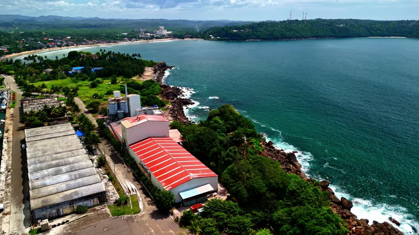 Aerial view of industrial buildings with red roofs situated along the rocky coastline of Galle, Southern Province, Sri Lanka.