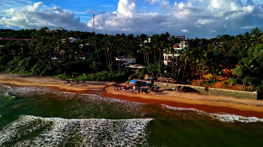 Aerial view of Madiha Beach with palm trees, coastal vegetation, and buildings along the shoreline in Matara, Southern Province, Sri Lanka.