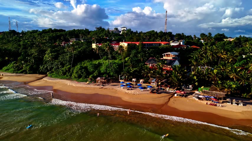 Aerial view of Madiha Beach with golden sand, palm trees, and coastal buildings in Matara, Southern Province, Sri Lanka.