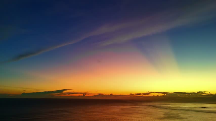 Aerial view of sunset over Madiha Beach with golden light reflecting on the ocean surface and colorful clouds in the sky in Matara, Southern Province, Sri Lanka.
