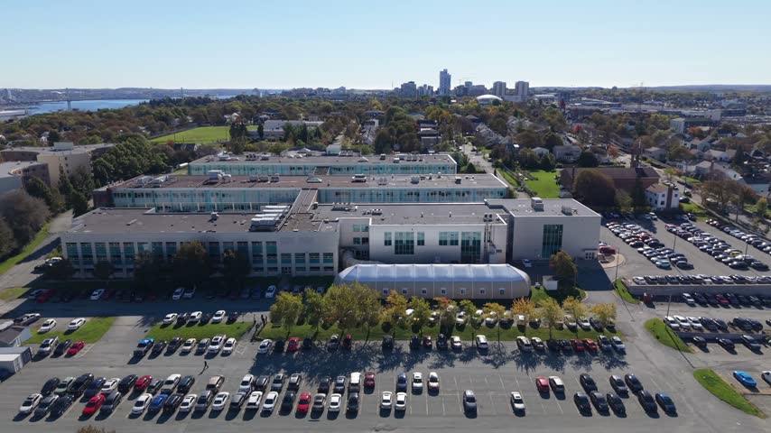 An elevated view looks across the Institute of Technology in Halifax, Nova Scotia, Canada, revealing its modern buildings, surrounding streets, and leafy grounds on a clear autumn day.