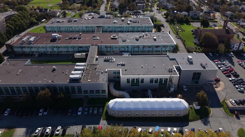 An elevated view surveys the Institute of Technology in Halifax, Nova Scotia, Canada, with campus buildings, parking lots, surrounding homes, and autumn trees under clear daylight.