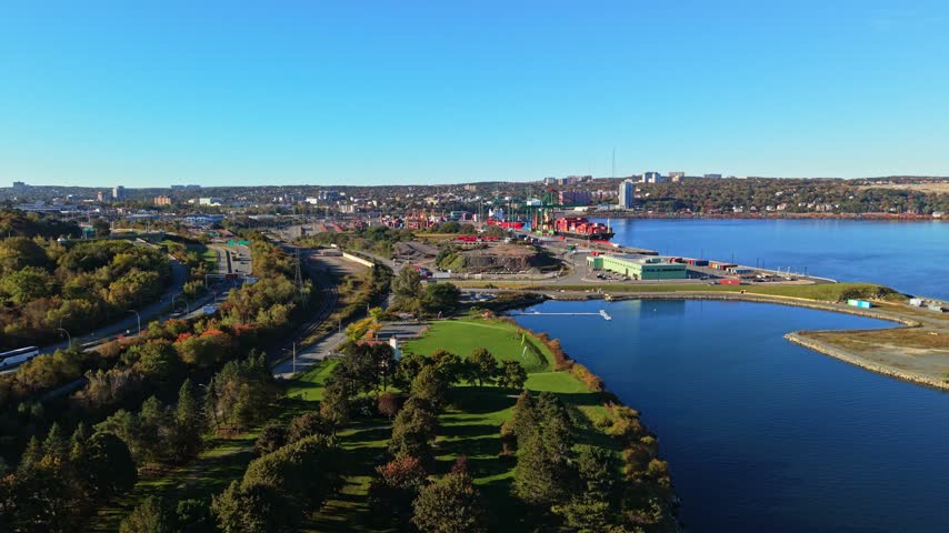 A high aerial view reveals ships, colorful containers and waterfront facilities around Halifax Harbour in Nova Scotia, Canada, beneath a clear blue sky.