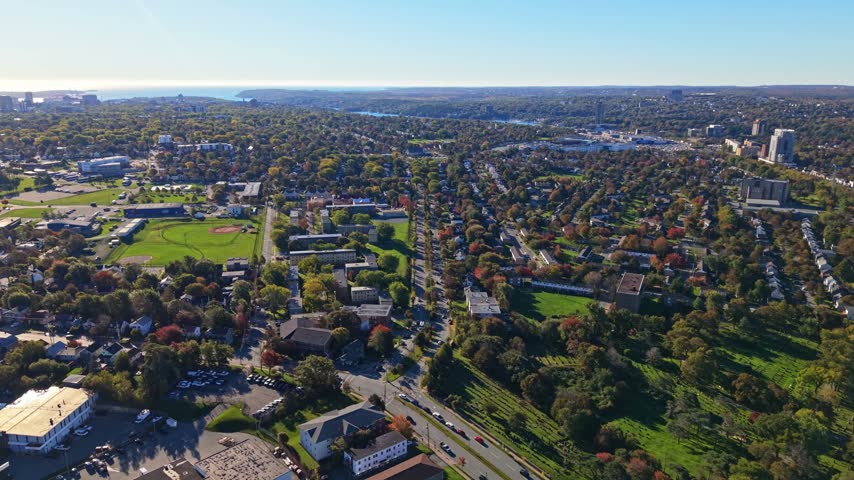 An aerial view of a road interchange and moving traffic amid green spaces and homes in Halifax, Nova Scotia, Canada, in daylight.