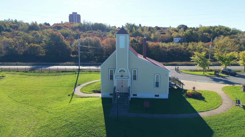 An aerial view circles the Africville Museum in Halifax, Nova Scotia, revealing its white building, green grounds, and quiet surroundings, a landmark honoring Africville