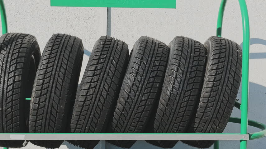 New car winter tires for sale lining up on a green rack at a retail service store showing tread pattern