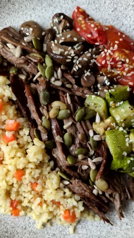 A bowl with beef, porridge, mushrooms, vegetables, sauce, and spices. Beef bowl
