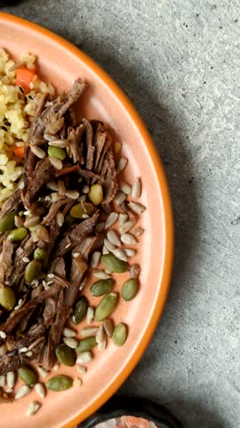 A bowl with beef, porridge, mushrooms, vegetables, sauce, and spices. Beef bowl